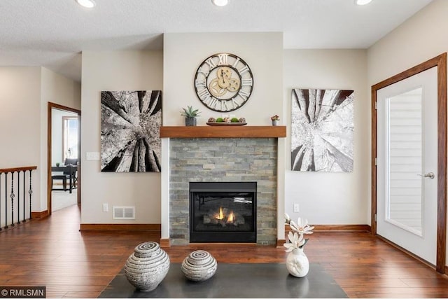 living room with a fireplace, dark hardwood / wood-style floors, and a textured ceiling