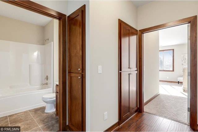 bathroom with shower / bathing tub combination, tile flooring, and toilet