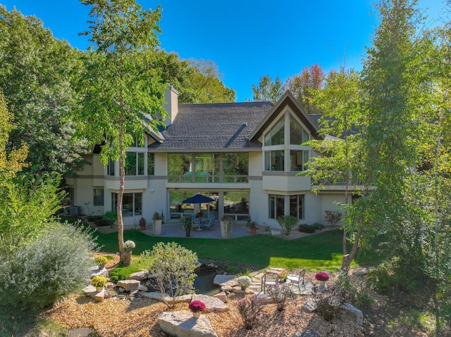 rear view of property featuring a lawn, a balcony, and a patio