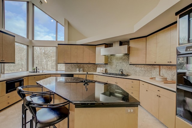 kitchen featuring a center island, wall chimney exhaust hood, a kitchen bar, light tile patterned floors, and black appliances