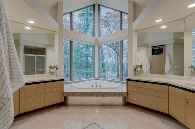 bathroom with plus walk in shower, a towering ceiling, vanity, and plenty of natural light