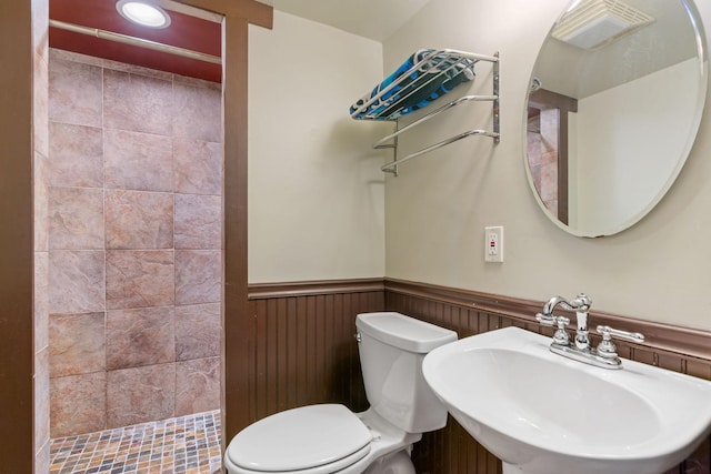 bathroom featuring sink, a tile shower, and toilet