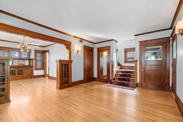 entryway with ornamental molding, light wood-type flooring, and a chandelier