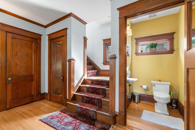 entryway with light hardwood / wood-style floors and crown molding