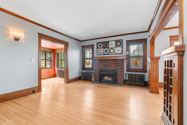 living room featuring light hardwood / wood-style floors, a brick fireplace, ornamental molding, and radiator