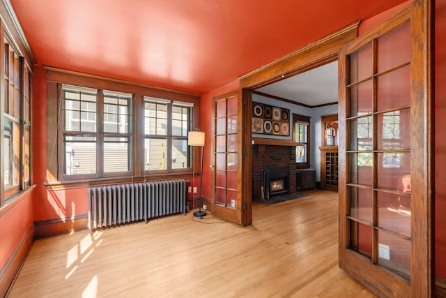 interior space featuring a brick fireplace, ornamental molding, light hardwood / wood-style flooring, and radiator heating unit