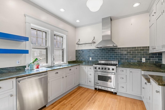 kitchen featuring appliances with stainless steel finishes, white cabinetry, island range hood, and sink