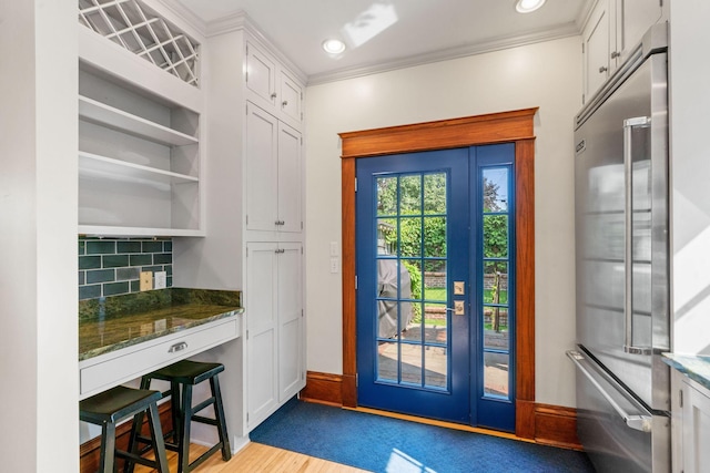 entryway with light wood-type flooring and crown molding