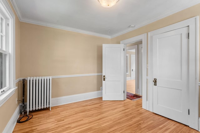 unfurnished bedroom featuring light hardwood / wood-style floors, crown molding, and radiator