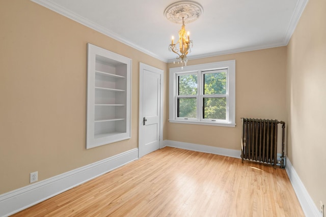 empty room with a chandelier, light wood-type flooring, crown molding, radiator, and built in shelves