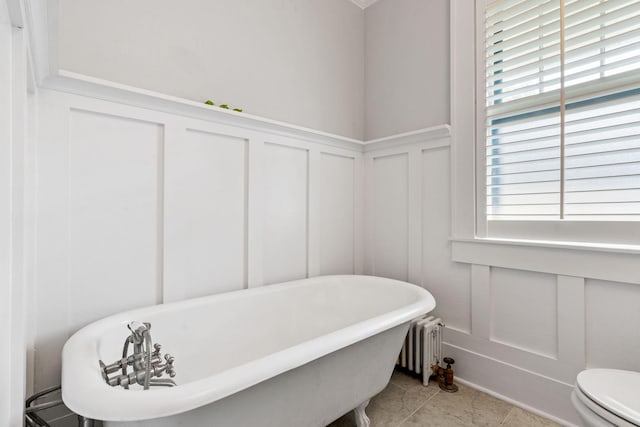 bathroom featuring toilet, a tub, radiator, and tile patterned floors