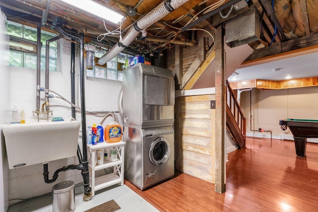 laundry area with billiards, wood-type flooring, stacked washer and clothes dryer, and sink