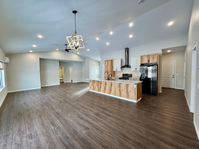 kitchen with black appliances, wall chimney exhaust hood, dark wood-type flooring, hanging light fixtures, and a center island with sink