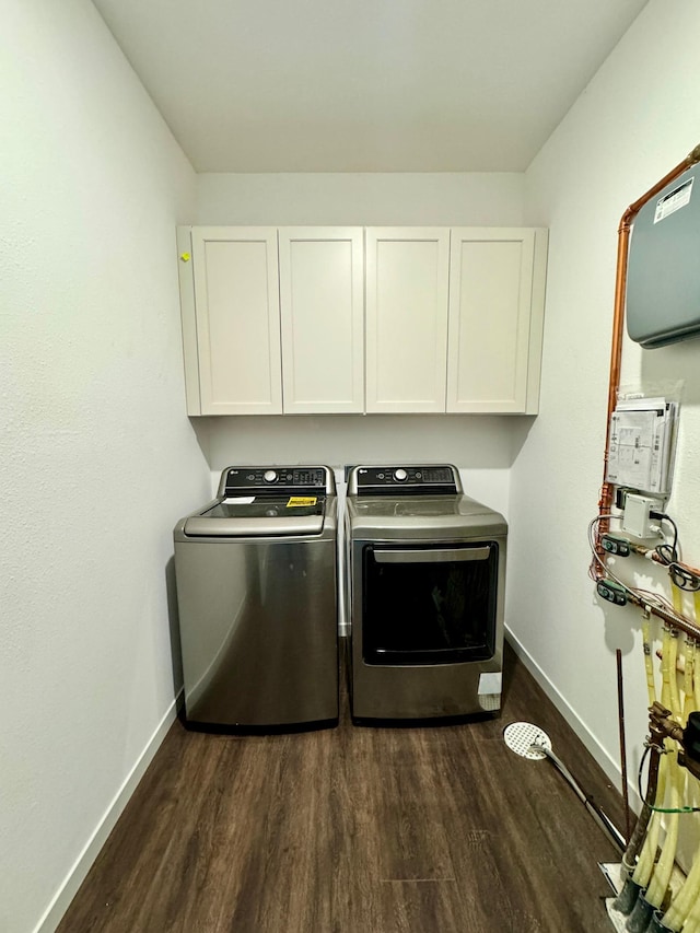 washroom with washing machine and dryer, dark hardwood / wood-style flooring, and cabinets