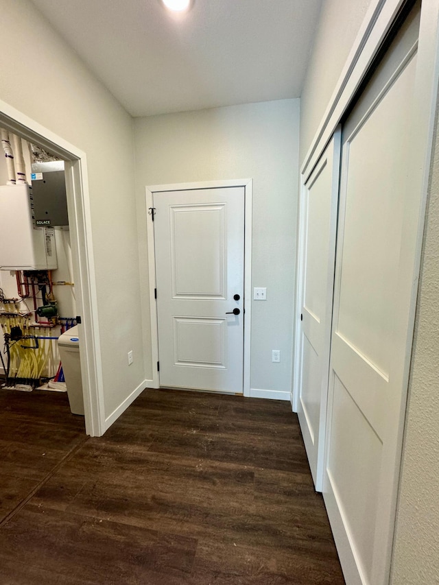 hallway featuring dark wood-type flooring and water heater