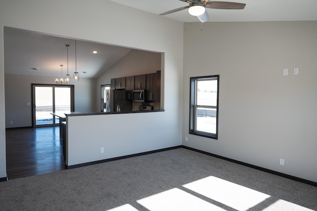 kitchen with ceiling fan, appliances with stainless steel finishes, dark colored carpet, decorative light fixtures, and vaulted ceiling