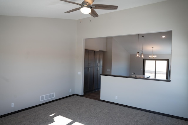 unfurnished room with dark colored carpet, vaulted ceiling, and ceiling fan with notable chandelier