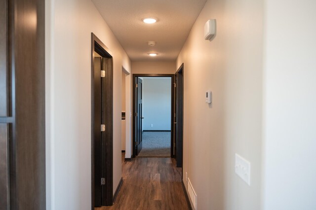 hallway with dark wood-type flooring and a textured ceiling