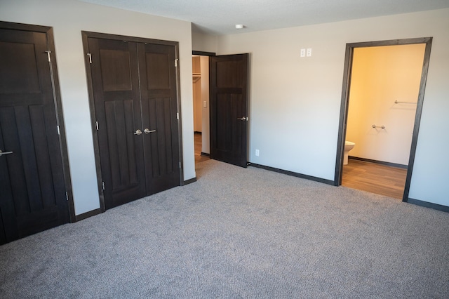 unfurnished bedroom with light carpet, ensuite bath, and a closet