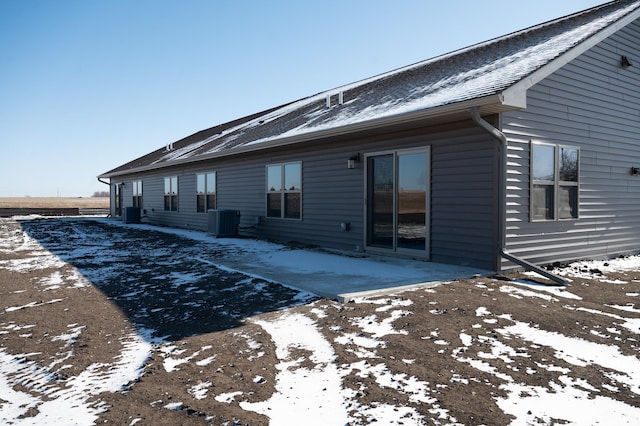 snow covered rear of property with cooling unit and a patio