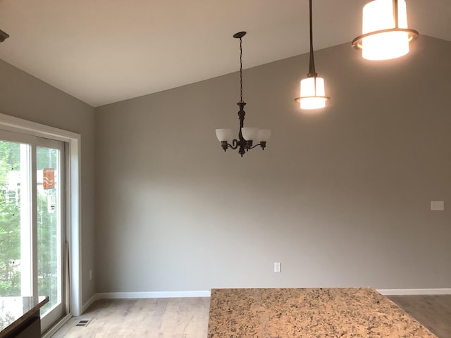 unfurnished dining area with lofted ceiling, a chandelier, and hardwood / wood-style flooring