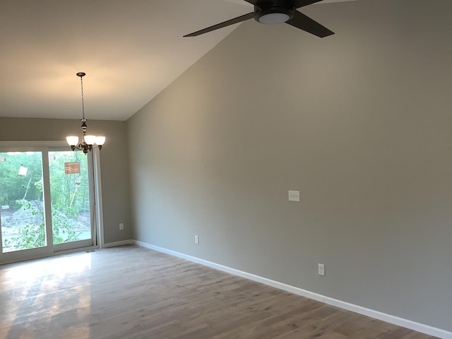 spare room with ceiling fan with notable chandelier, lofted ceiling, and wood-type flooring