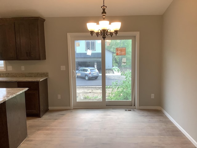 unfurnished dining area with an inviting chandelier and light hardwood / wood-style floors