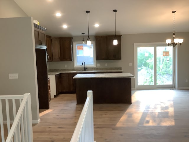 kitchen with light hardwood / wood-style flooring, hanging light fixtures, a center island, and dark brown cabinets