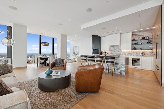 living room featuring a wall of windows, light hardwood / wood-style flooring, and beverage cooler