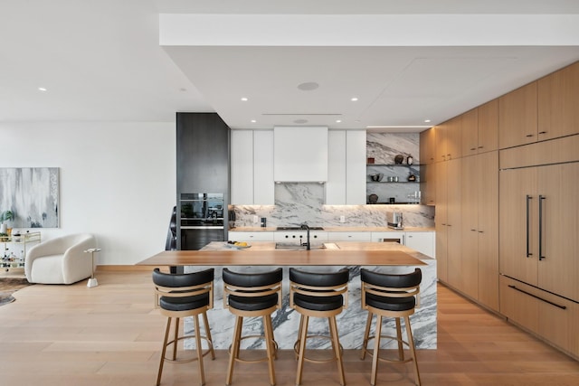 kitchen with light hardwood / wood-style floors, a breakfast bar, and light brown cabinets