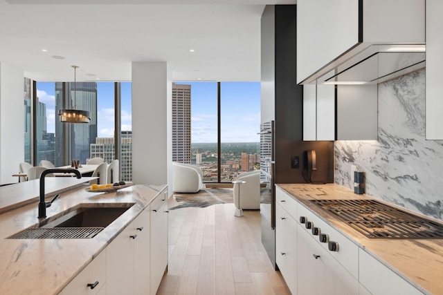 kitchen featuring sink, white cabinetry, decorative light fixtures, and light hardwood / wood-style floors