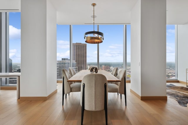 dining area featuring a wall of windows, light hardwood / wood-style flooring, and a notable chandelier