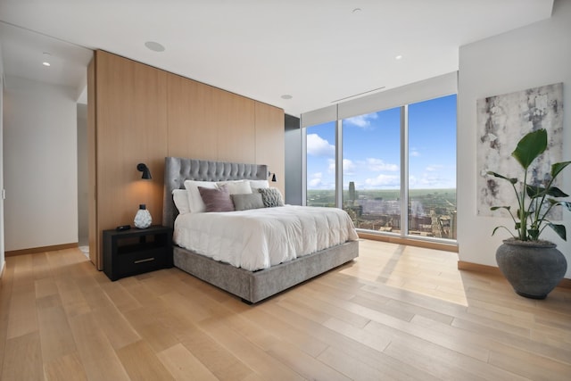 bedroom featuring light wood-type flooring and floor to ceiling windows