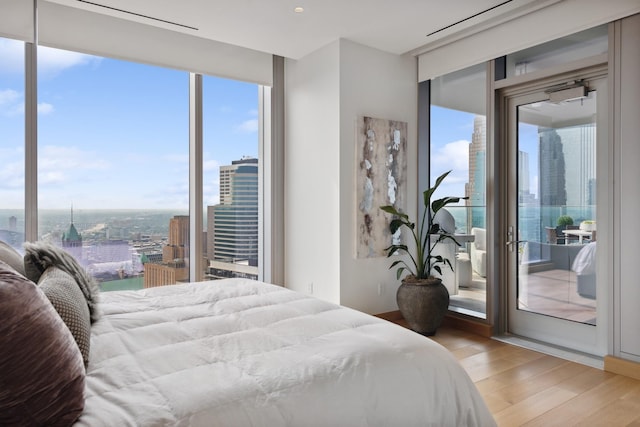 bedroom featuring multiple windows, hardwood / wood-style floors, and access to exterior