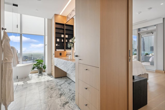 bathroom with vanity, a wall of windows, and a washtub