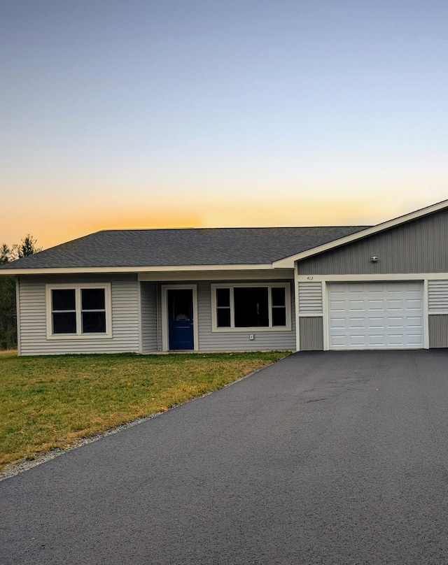 ranch-style house featuring a garage and a lawn