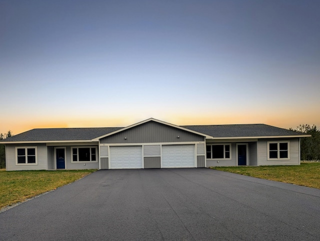 single story home featuring a garage and a lawn