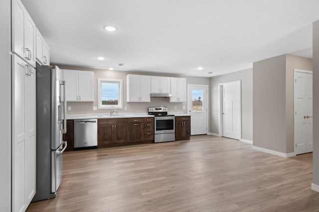 kitchen featuring stainless steel appliances, dark brown cabinets, sink, and light wood-type flooring