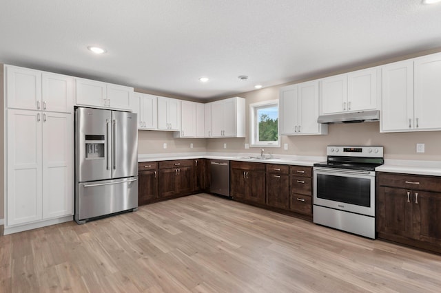 kitchen featuring white cabinetry, light wood-type flooring, appliances with stainless steel finishes, dark brown cabinetry, and sink