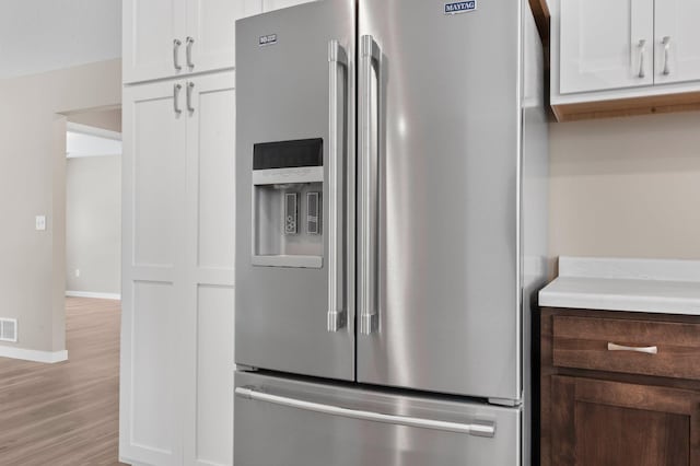 kitchen featuring light hardwood / wood-style flooring, stainless steel fridge with ice dispenser, and white cabinets