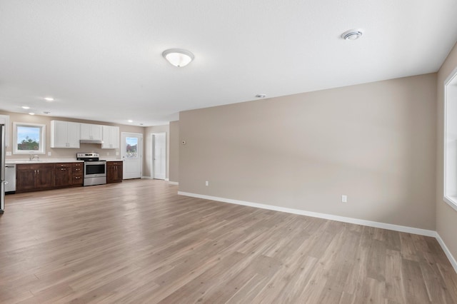 unfurnished living room featuring sink and light hardwood / wood-style flooring