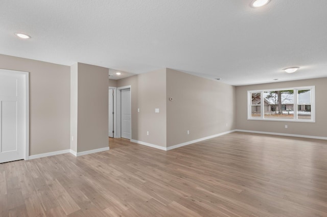 spare room featuring a textured ceiling and light hardwood / wood-style flooring