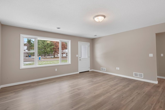 empty room with wood-type flooring and a textured ceiling