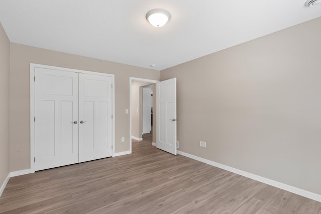 unfurnished bedroom featuring light hardwood / wood-style flooring and a closet