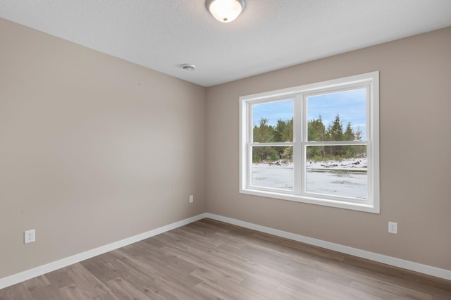 spare room featuring a textured ceiling and light hardwood / wood-style flooring