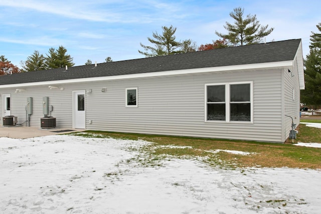 snow covered property with central AC and a patio area