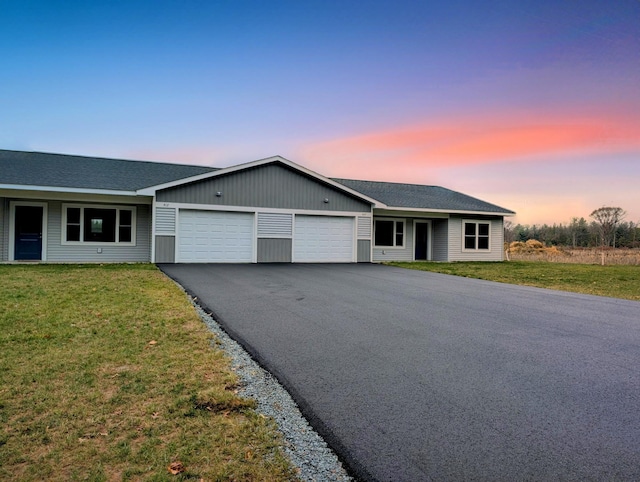 ranch-style home featuring a garage and a lawn