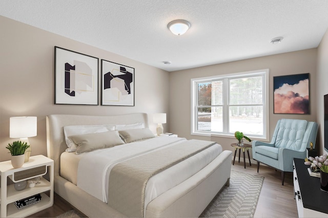 bedroom with hardwood / wood-style floors and a textured ceiling