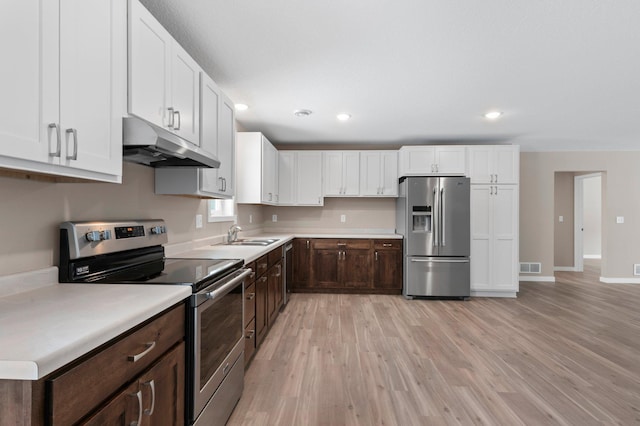 kitchen with appliances with stainless steel finishes, dark brown cabinets, light hardwood / wood-style floors, and white cabinets