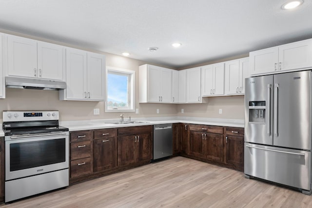 kitchen with dark brown cabinetry, light hardwood / wood-style floors, white cabinetry, sink, and appliances with stainless steel finishes